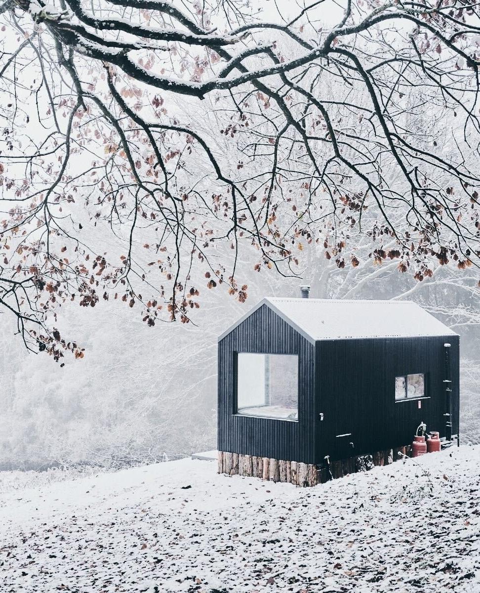 Black cabin in snowy Australia offers tranquility.