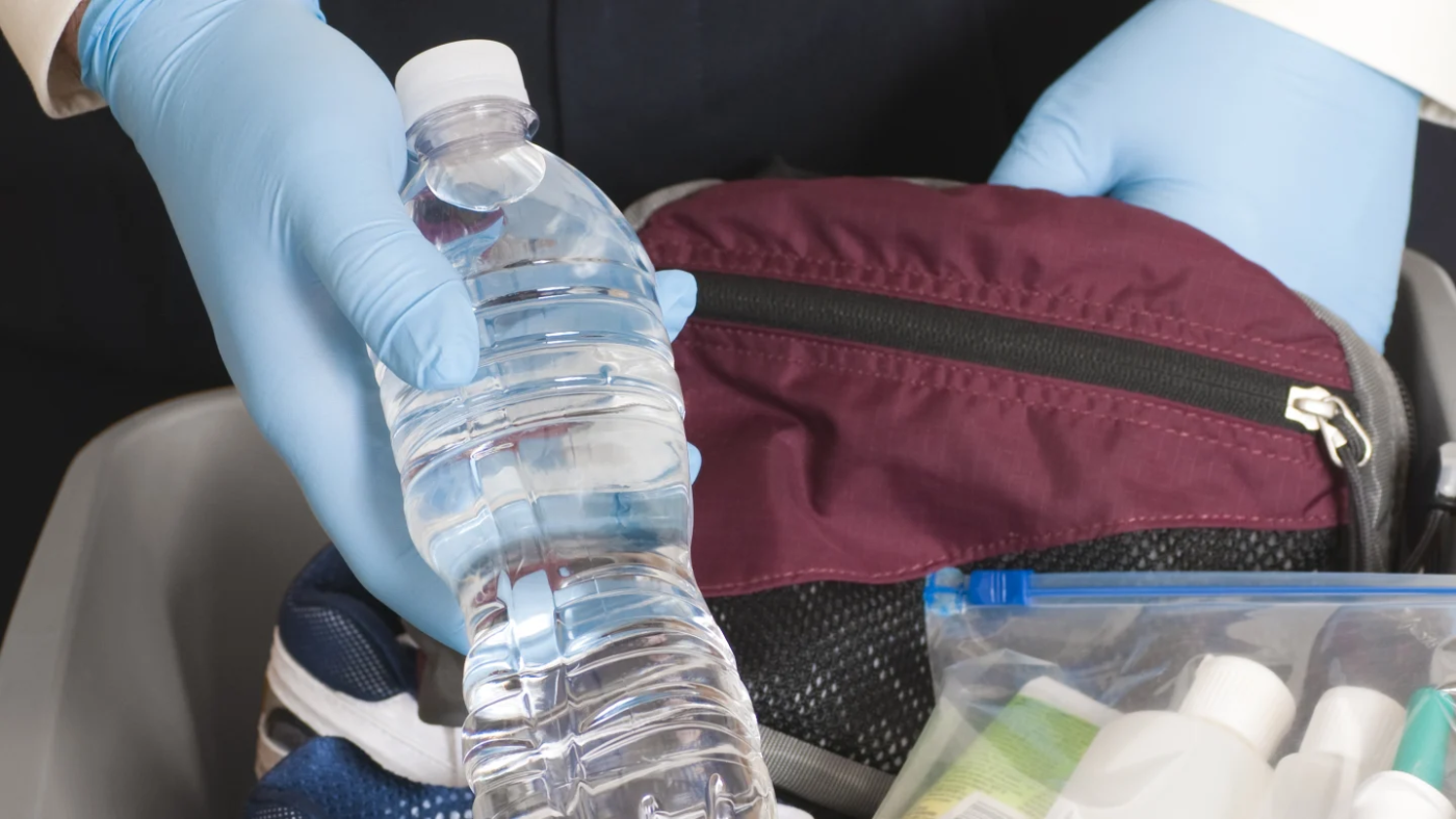 A water bottle being pulled out of luggage by a TSA agent. 