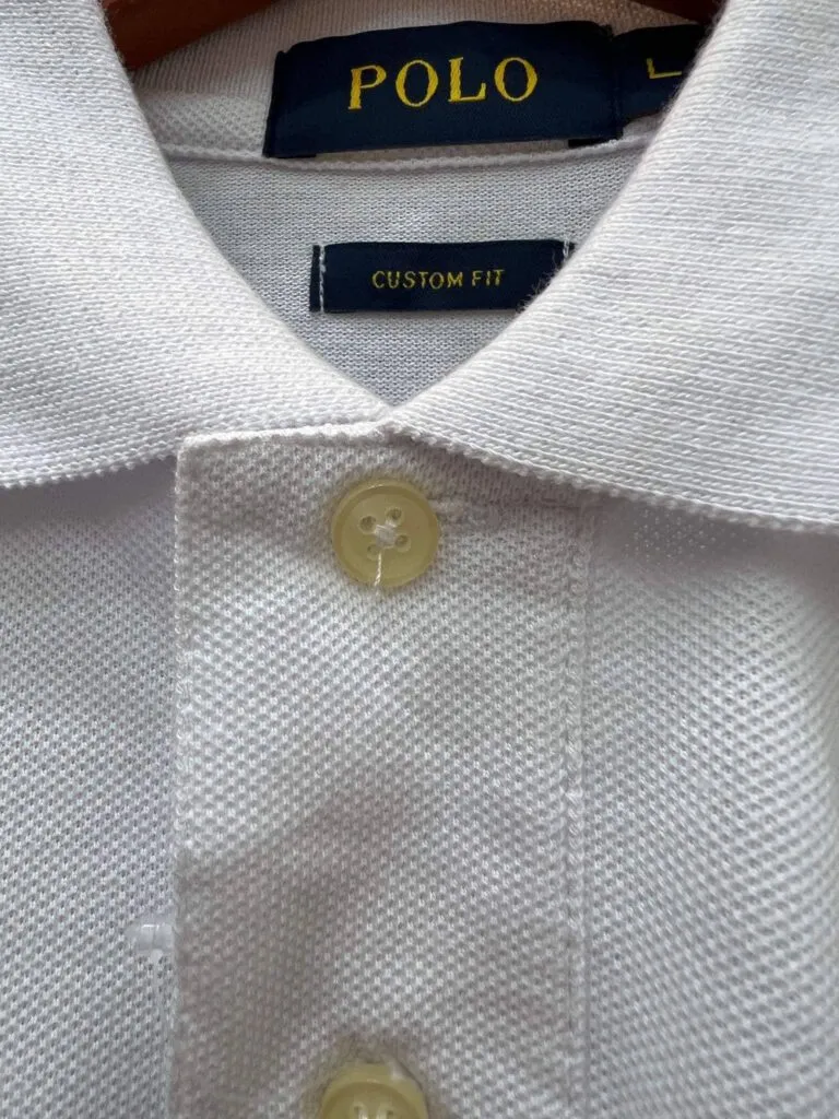 A poorly sewn button on a fake Rlaph Lauren polo shirt, with neck label. 