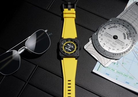 Bell & Ross BR-03 Helipad on yellow rubber strap with aviator sunglasses, an E6B flight computer and a navigation chart