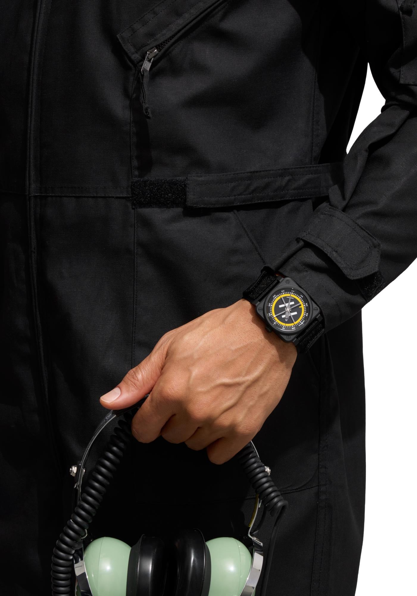 Bell & Ross BR-03 Helipad worn on the wrist with the yellow rubber strap, black bomber jacket and yellow hoodie